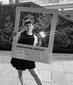 a woman holding up a sign in front of graffiti