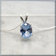 Gorgeous sky blue color is reflected in this lab created blue spinel necklace. The oval cut sparkles and shows off the lovely blue shade of the stone to it's best advantage. Feminine and so pretty - the simple setting really lets the stone be the star. The lab created blue spinel oval stone is 9x7mm. Set in a sterling silver basket setting to allow light to flow through the stone. Sterling silver curb chain included. Items are shown larger in pictures to show detail - please note the dimensions. Oval Blue Topaz Birthstone Necklace, Oval Blue Topaz Sapphire Necklace, Light Blue Oval Gemstone Necklaces, Blue Oval Faceted Necklaces, Blue Oval Faceted Necklace, Oval Blue Topaz Necklace, Blue Topaz Oval Necklace, Blue Oval Birthstone Necklaces, Blue Oval Birthstone Necklace