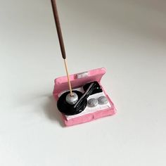 a pink box filled with makeup brushes and eyeliners on top of a white table