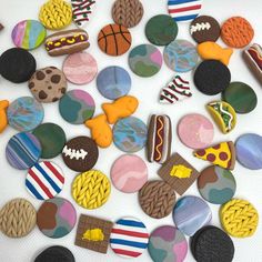 a pile of different colored cookies sitting on top of a white table covered in icing