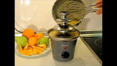 an electric blender sitting on top of a counter next to oranges and apples