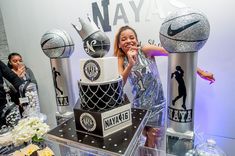 a woman standing in front of a cake with basketballs on it at a party