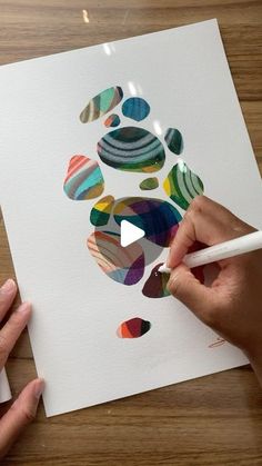 two hands are drawing on paper with colored circles and shapes that appear to be painted