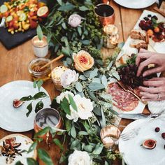 people sitting at a wooden table with plates and flowers on it, eating pizzas