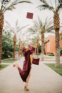 a woman in a graduation gown is throwing her cap into the air while standing on one leg