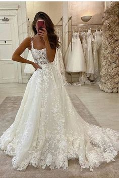 a woman taking a selfie in her wedding dress while looking at her cell phone