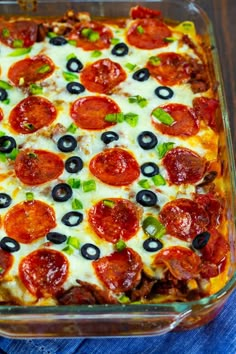 a pizza casserole with pepperoni, olives and green peppers in a glass dish