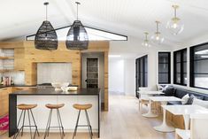 an open concept kitchen and living room with wood paneling, white countertops and black accents