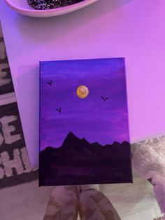 someone is holding up a purple painting with black birds flying in the sky above them