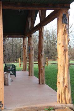 an outdoor covered area with benches and wooden posts in the background, along with green grass