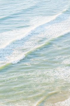 a man riding a surfboard on top of a wave covered ocean next to the beach