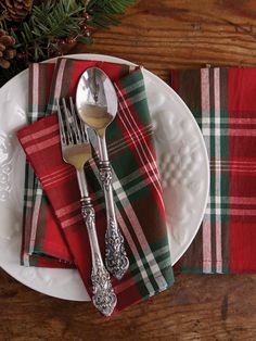 a white plate topped with silverware next to a red and green plaid table cloth