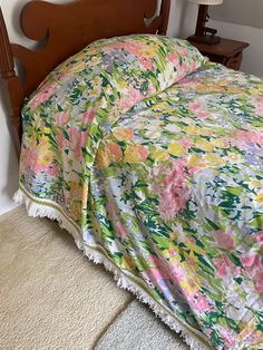 an unmade bed with a floral comforter and matching pillowcase, along with a wooden headboard