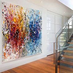 an abstract painting hangs on the wall next to a stair case in a modern home