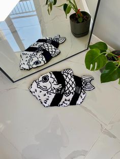 two black and white fish shaped rugs sitting on top of a counter next to a mirror