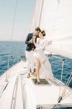 a man and woman standing on the deck of a sailboat