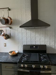 a stove top oven sitting inside of a kitchen next to a wall mounted pot rack