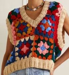 a woman wearing a multicolored crocheted sweater and jeans with her hands on her hips