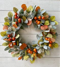 a wreath with oranges and green leaves on a white wooden background, ready to be used as an ornament