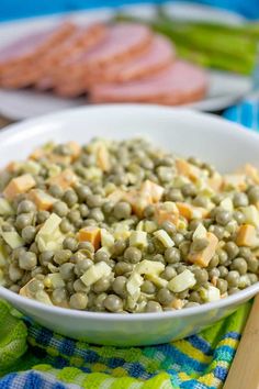 a white bowl filled with green lentils and cheese on top of a blue table cloth