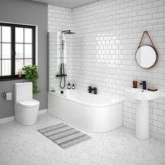 a modern bathroom with white tile walls and flooring, including a tub, toilet, sink, and mirror