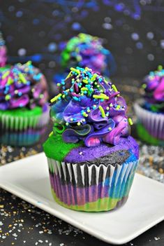 cupcakes with colorful frosting and sprinkles on a white plate