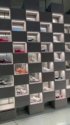 a display case with many pairs of shoes on shelves in front of a metallic wall