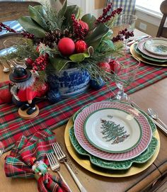 the table is set for christmas dinner with plaid napkins and place settings on it