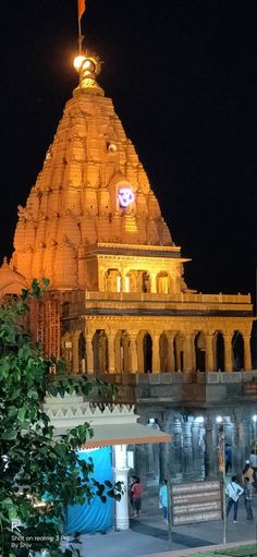 an ornate building lit up at night with people walking around