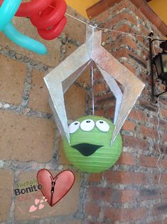 some balloons are hanging from the ceiling near a brick wall and a green ballon