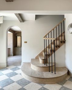 a staircase in the middle of a room with checkered flooring and white walls