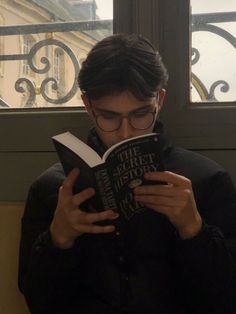 a man reading a book in front of a window