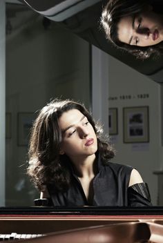 a woman sitting at a piano with her eyes closed