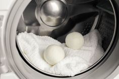 three balls of wool are sitting in the front of a washing machine, next to a white towel