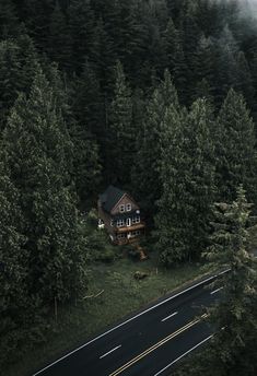 an aerial view of a house in the middle of a forest with trees surrounding it