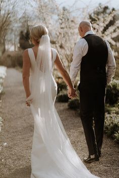 Bride in back button detail wedding dress with pearl embellished veil walking holding hands with groom in black tie for luxe hotel wedding Button Back Wedding Dress, Detail Wedding Dress, Pastel Pink Bridesmaid Dresses, Pale Pink Bridesmaids, Pale Pink Bridesmaid Dresses, Groom And Groomsmen Outfits, Veil Ideas, Veil Pearl, Embellished Veil