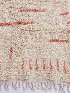 a white rug with red lines on it and fringes around the edges is shown