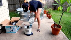 a woman bending over to pick up something from a bucket