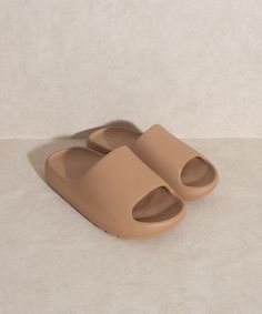 a pair of beige slippers sitting on top of a white floor next to a wall