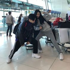 two people standing next to each other at an airport