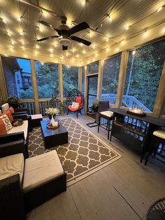 a living room filled with lots of furniture and lights hanging from the ceiling next to windows