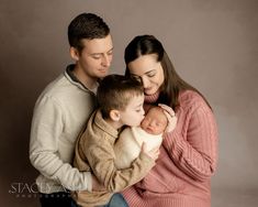 a man and woman holding a baby in their arms while sitting next to each other