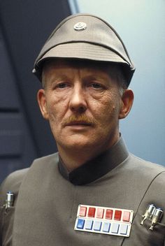 a man in uniform is looking at the camera while wearing a hat with buttons on it