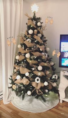 a decorated christmas tree in the corner of a room with a television on and handprinted decorations