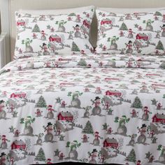 a bed covered in white and red christmas themed bedspreads with animals on them