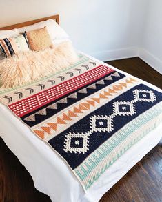 a white bed topped with a blanket and pillows next to a wooden headboard on top of a hard wood floor