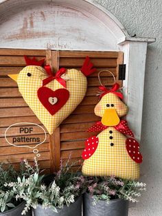 two potted plants are sitting in front of a wooden sign with hearts on it