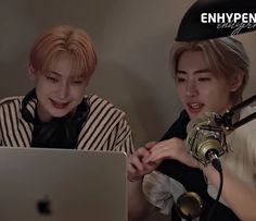 two young men sitting in front of a laptop computer