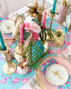 the table is set with pink, blue and gold place settings