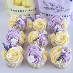 cupcakes decorated with yellow and purple frosting on a table next to a bag of powdered sugar